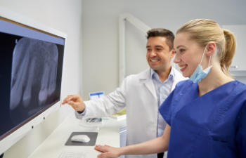 doctor with assistant looking at a patiens x-ray